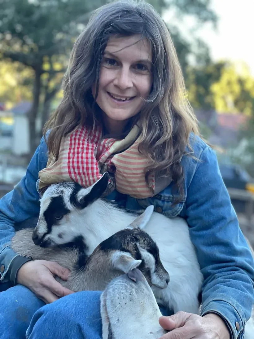 Shepherdess Billie Thibodeau holding a young goat